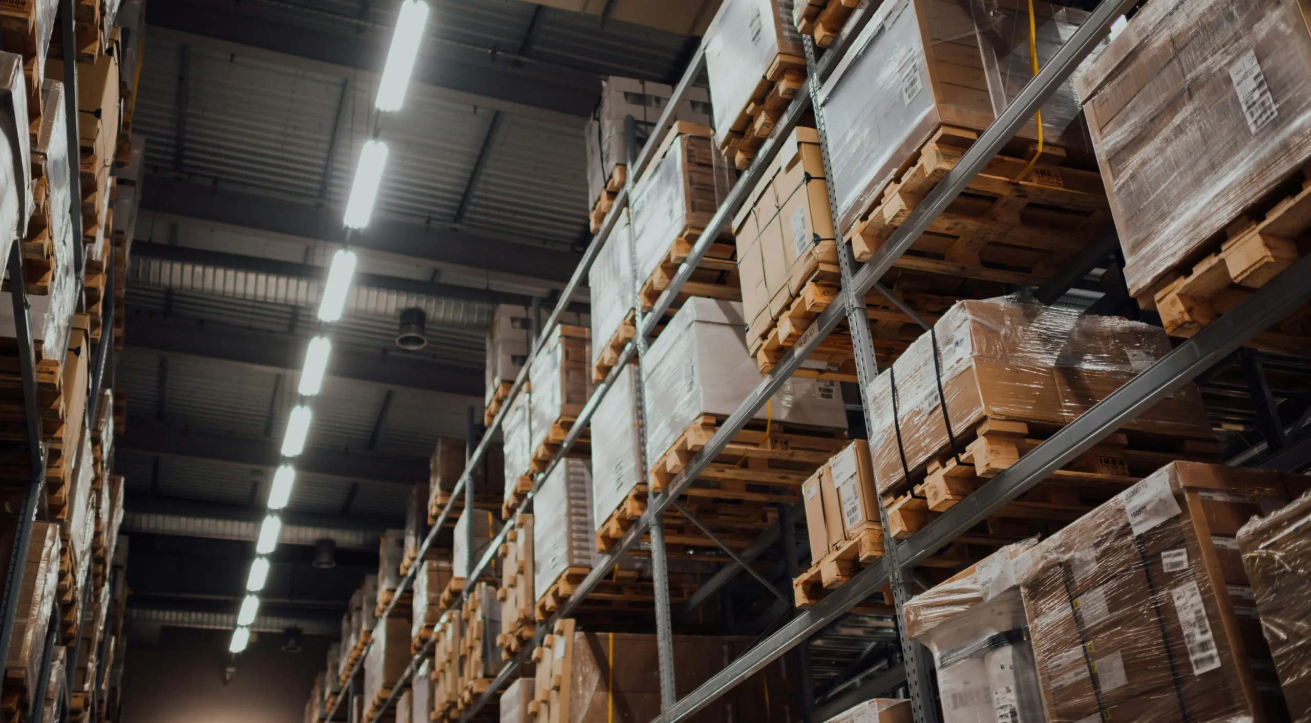 Shrink-wrapped pallets of boxed stock stacked high in a distribution warehouse